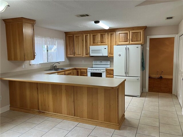 3837 Coventry St, Slidell, LA 70458 - kitchen with white appliances, a sink, light countertops, a peninsula, and brown cabinetry