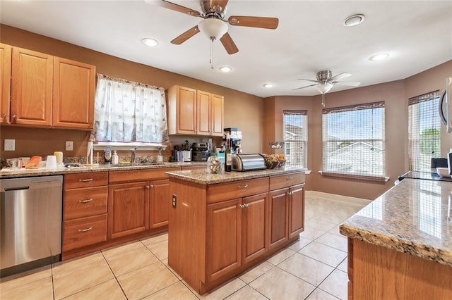 kitchen featuring a ceiling fan, appliances with stainless steel finishes, a sink, and light stone counters