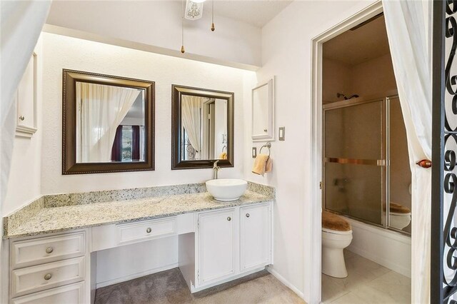 bathroom featuring vanity, combined bath / shower with glass door, and toilet