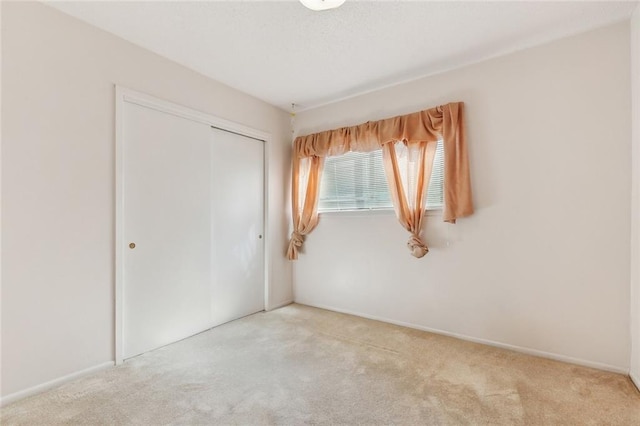unfurnished bedroom with carpet floors, baseboards, and a closet