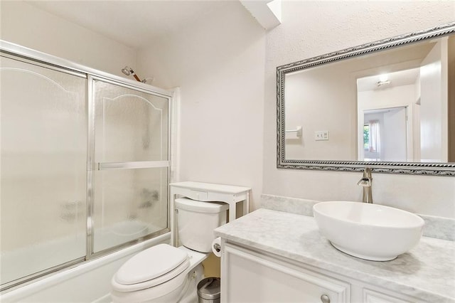 full bath featuring toilet, combined bath / shower with glass door, and vanity