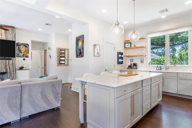 kitchen with a sink, gray cabinetry, dark wood-style floors, and visible vents