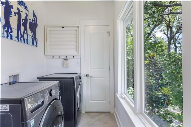 washroom with washing machine and clothes dryer, laundry area, baseboards, and light tile patterned floors