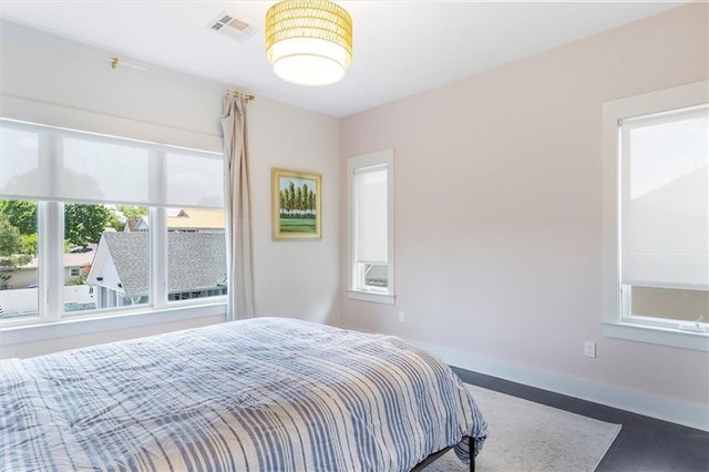 bedroom featuring baseboards, visible vents, and wood finished floors