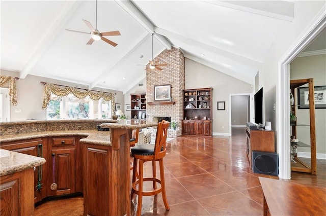 bar with dark tile patterned floors, ceiling fan, a brick fireplace, baseboards, and lofted ceiling with beams