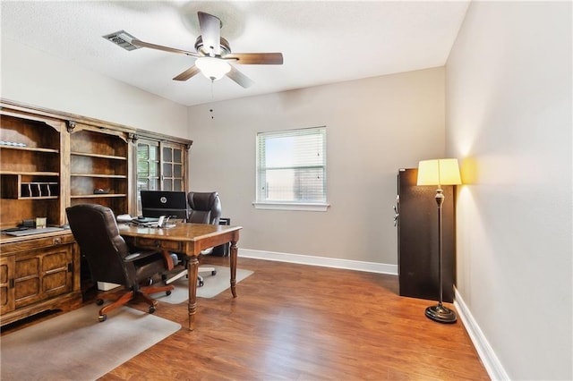 office area featuring baseboards, a ceiling fan, wood finished floors, and visible vents
