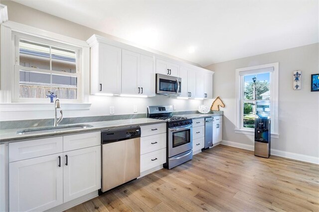 20 Thrasher St, New Orleans, LA 70124 - kitchen featuring light wood-type flooring, a sink, white cabinetry, and appliances with stainless steel finishes