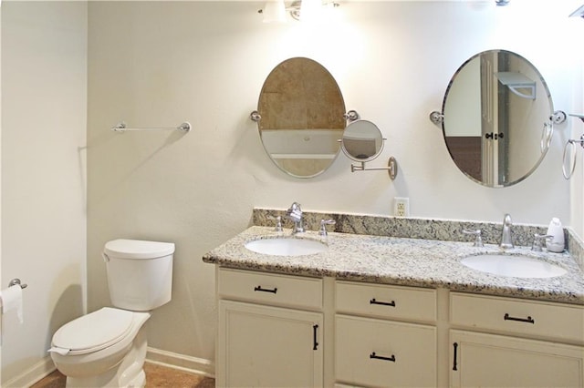full bathroom with double vanity, toilet, baseboards, and a sink