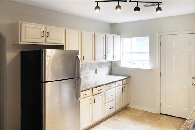 kitchen with visible vents, tasteful backsplash, light stone countertops, light tile patterned floors, and freestanding refrigerator