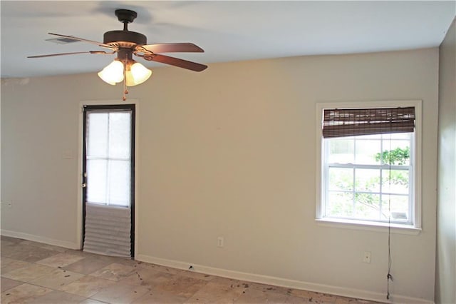 spare room featuring baseboards, plenty of natural light, and a ceiling fan