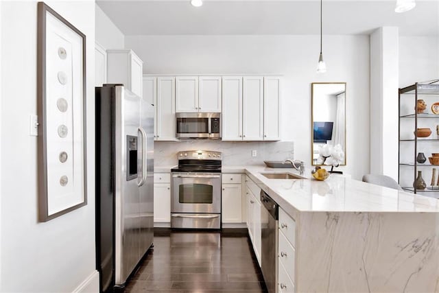 1201 Canal St Unit 416, New Orleans, LA 70112 - kitchen with backsplash, appliances with stainless steel finishes, a sink, a peninsula, and white cabinetry
