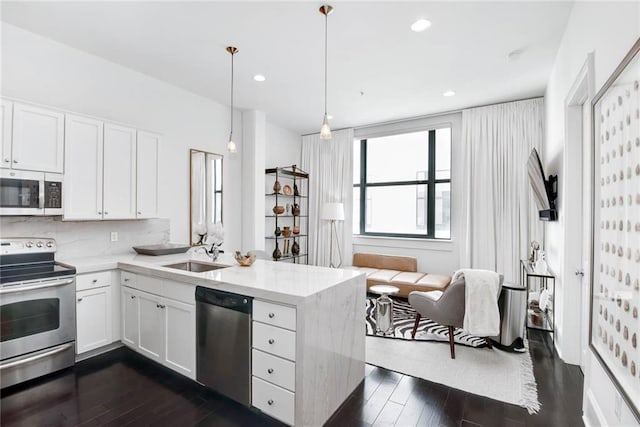 1201 Canal St Unit 416, New Orleans, LA 70112 - kitchen featuring a peninsula, dark wood-type flooring, white cabinets, a sink, and appliances with stainless steel finishes