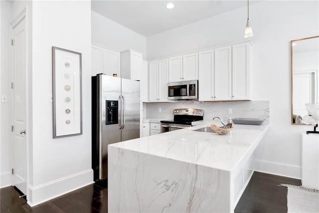 1201 Canal St Unit 416, New Orleans, LA 70112 - kitchen with white cabinets, appliances with stainless steel finishes, a sink, a peninsula, and baseboards