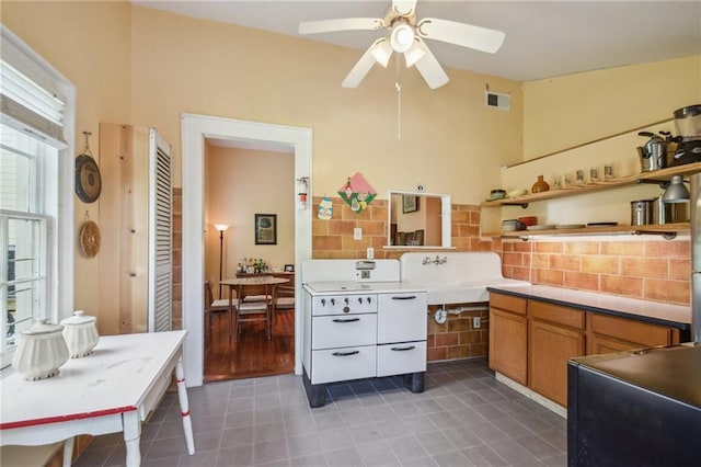 kitchen with a sink, lofted ceiling, light countertops, a ceiling fan, and light tile patterned floors