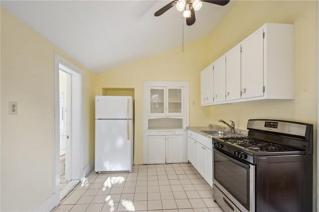 kitchen featuring a sink, freestanding refrigerator, white cabinetry, stainless steel range with gas cooktop, and lofted ceiling
