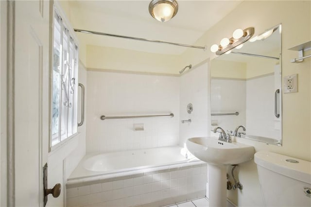 bathroom featuring a sink, tiled shower / bath, and toilet