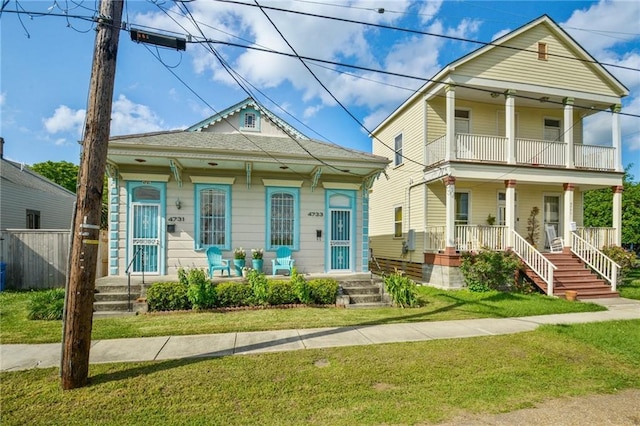 view of front of home with a balcony, fence, a porch, and a front yard
