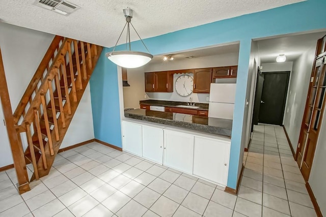2441 Chartres St, New Orleans, LA 70117 - kitchen featuring freestanding refrigerator, light tile patterned flooring, a textured ceiling, and visible vents