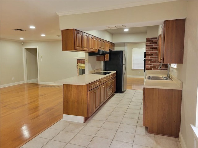 kitchen featuring freestanding refrigerator, visible vents, black electric stovetop, and a sink