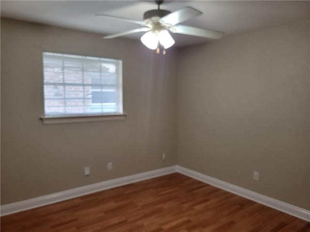 spare room with baseboards, ceiling fan, and wood finished floors