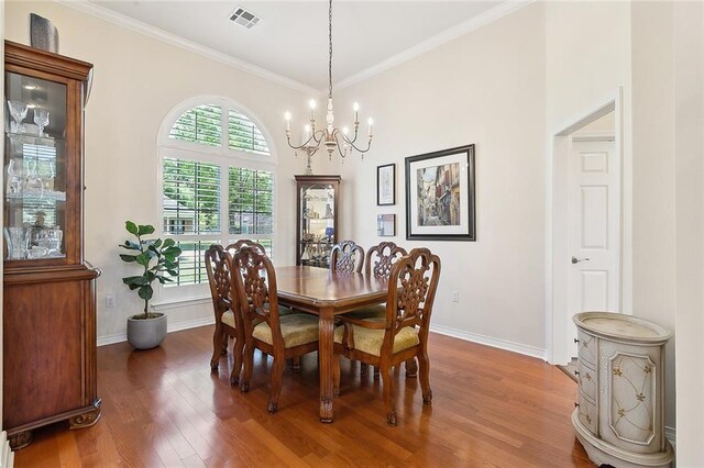 dining area with a chandelier, wood finished floors, baseboards, and crown molding