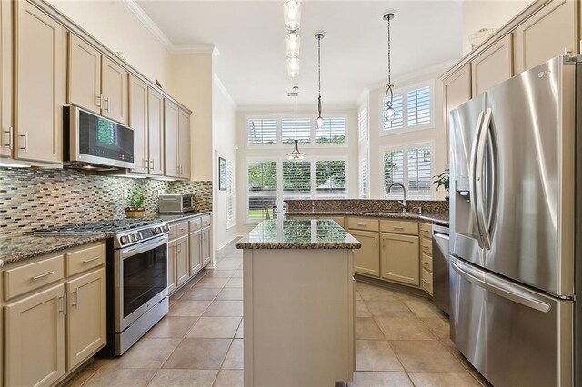 kitchen with appliances with stainless steel finishes, ornamental molding, a sink, a peninsula, and a center island