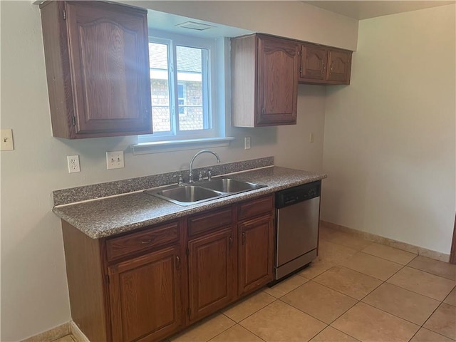 kitchen with stainless steel dishwasher, a sink, dark countertops, and light tile patterned floors