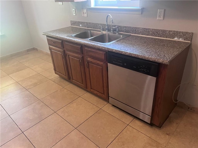 kitchen featuring stainless steel dishwasher, a sink, dark countertops, and light tile patterned floors