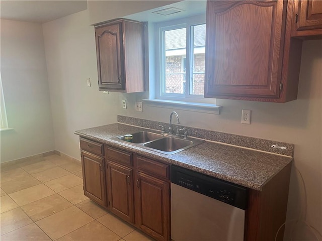 kitchen with dishwasher, a sink, dark countertops, light tile patterned floors, and baseboards