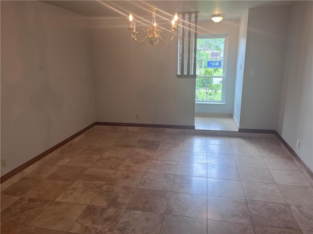 spare room with a chandelier and baseboards