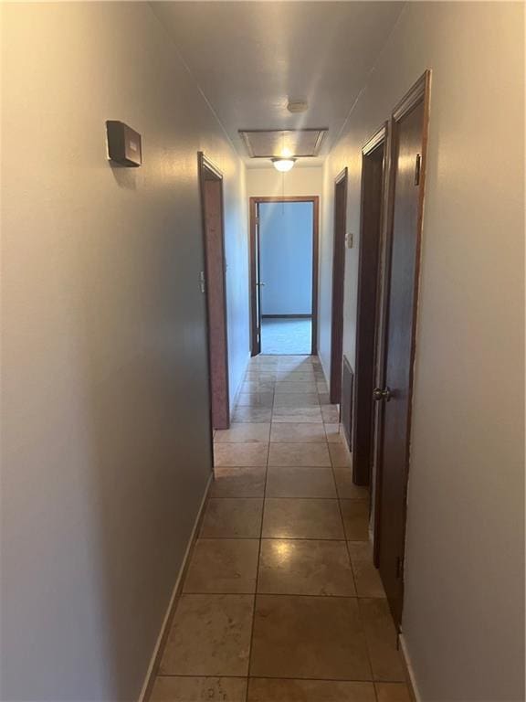 corridor featuring baseboards and light tile patterned flooring
