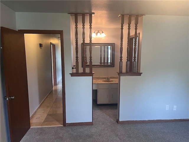 corridor featuring a sink, baseboards, and carpet