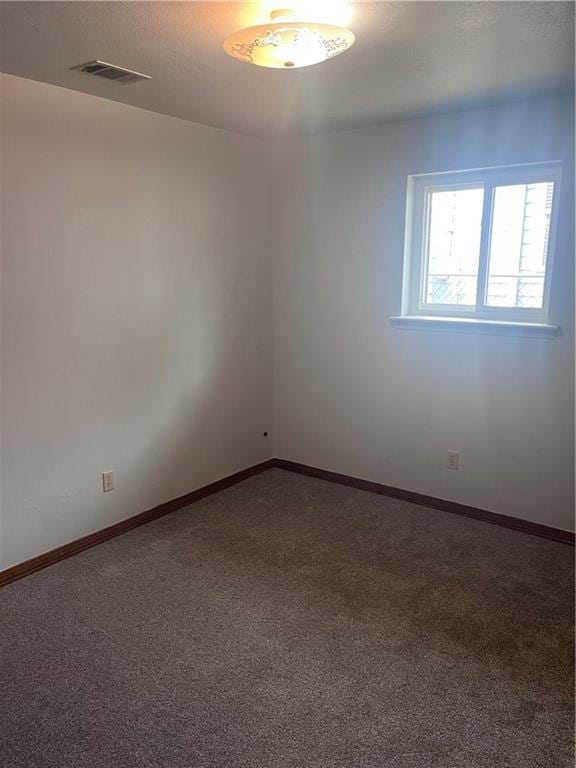 spare room featuring carpet, baseboards, and a textured ceiling