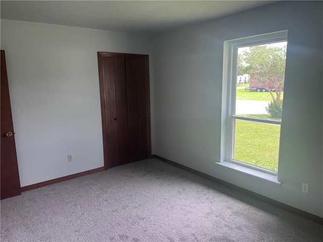 carpeted spare room with plenty of natural light and baseboards