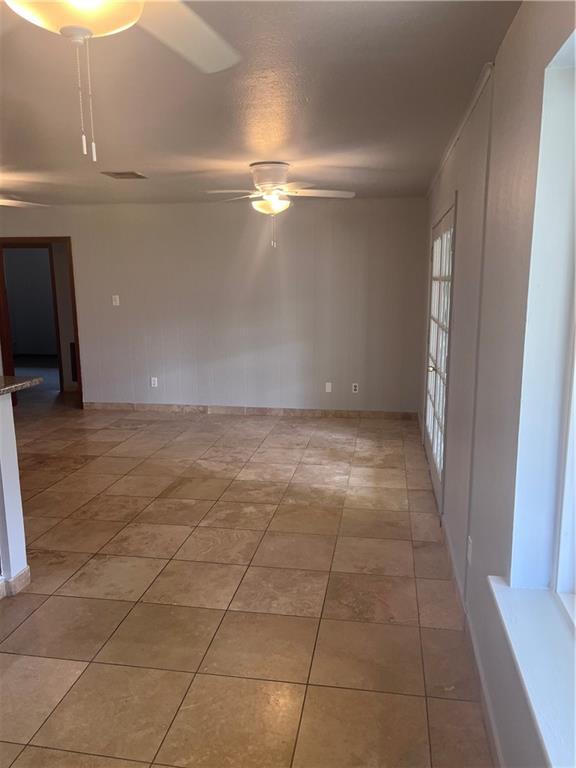 empty room with a ceiling fan and light tile patterned flooring