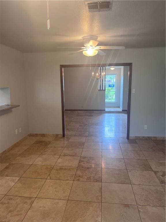 empty room with a ceiling fan, light tile patterned floors, and baseboards