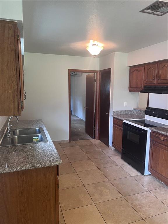 kitchen with electric range, a sink, light tile patterned floors, and range hood