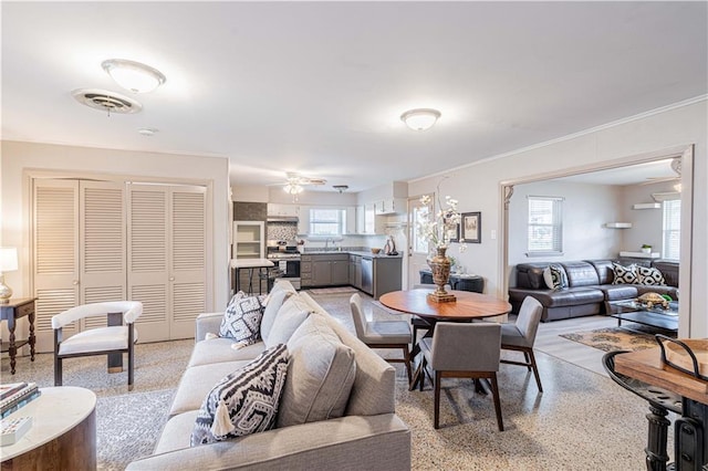 living room featuring light speckled floor, crown molding, a ceiling fan, and visible vents