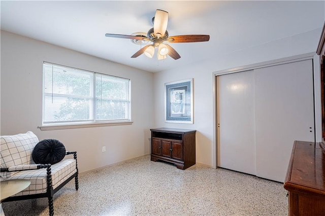 sitting room with baseboards, a ceiling fan, and light speckled floor