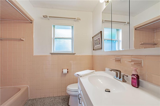 full bath featuring a healthy amount of sunlight, tile walls, wainscoting, and toilet