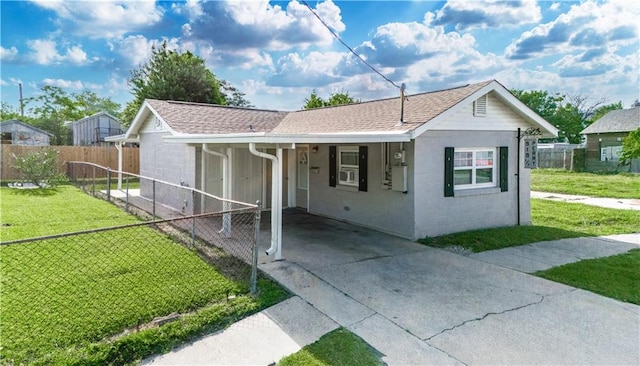 ranch-style home with fence, a front yard, roof with shingles, an attached carport, and concrete driveway