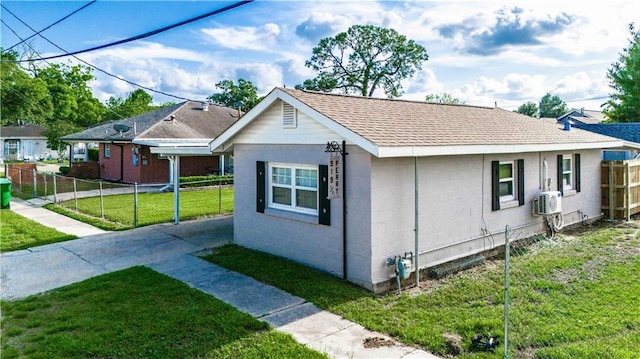 view of front facade featuring fence, a shingled roof, concrete block siding, and a front lawn