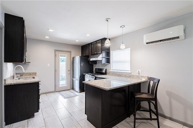kitchen with appliances with stainless steel finishes, a wall mounted AC, a sink, a peninsula, and under cabinet range hood