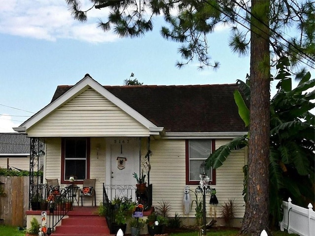 bungalow with roof with shingles, fence, and covered porch