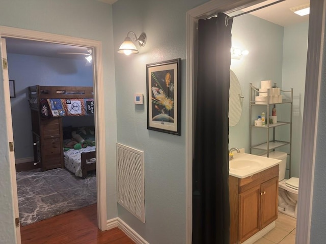 corridor with visible vents, a sink, and light wood finished floors