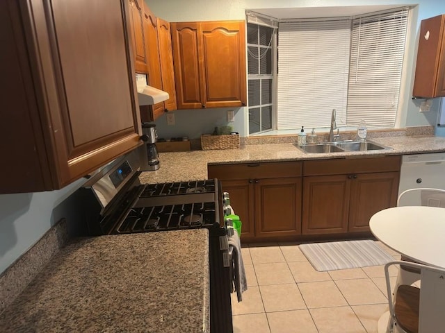 kitchen featuring brown cabinets, white dishwasher, light tile patterned flooring, gas stove, and a sink
