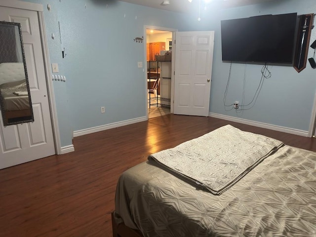 bedroom with baseboards, refrigerator, and wood finished floors