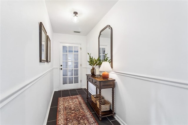 doorway to outside featuring dark tile patterned floors, baseboards, and visible vents