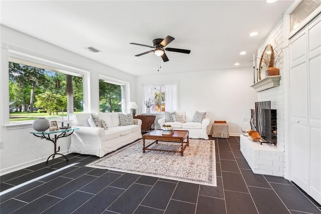 living area with dark tile patterned floors, a ceiling fan, visible vents, a brick fireplace, and recessed lighting