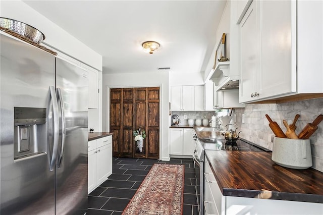 kitchen featuring decorative backsplash, dark tile patterned flooring, white cabinets, wood counters, and stainless steel appliances